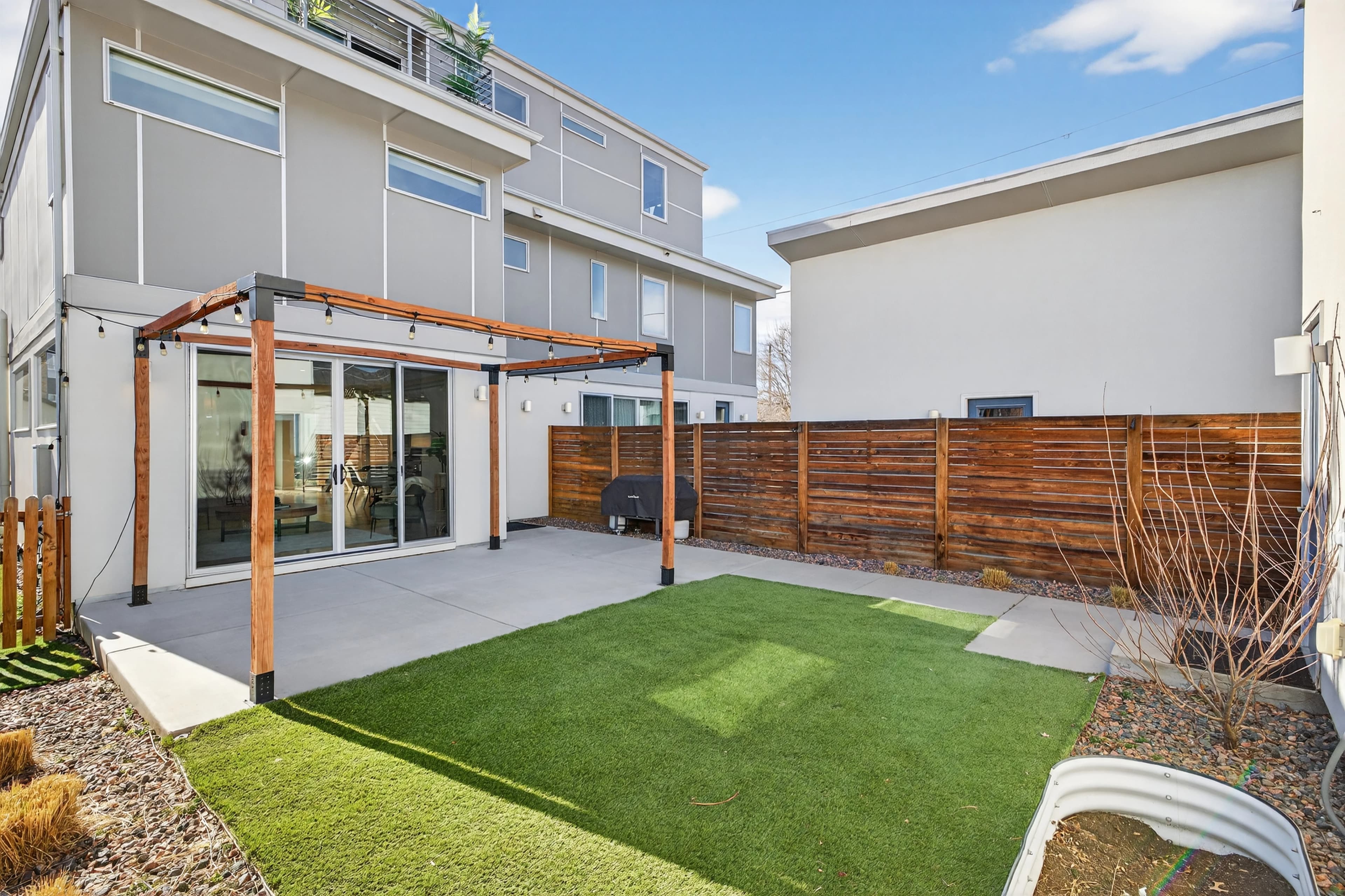 Private backyard with pergola, turf, and string lights.